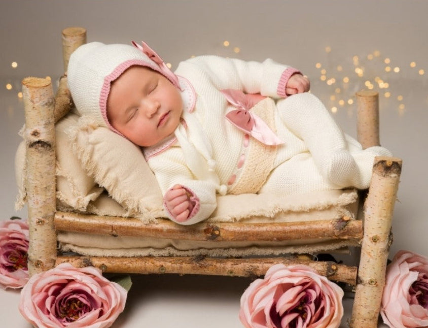 Newborn baby in a small bed with pink flowers and a soft background