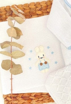 Set of baby clothing with bear design on a woven basket