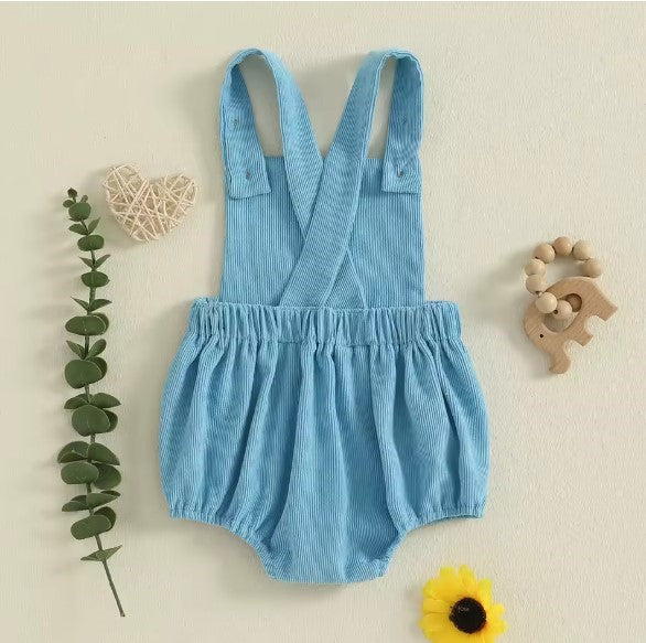 Blue baby romper with straps on a beige background