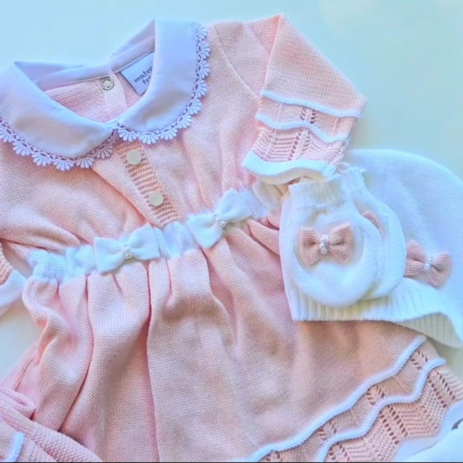 Pink baby dress with white lace details on a light blue background