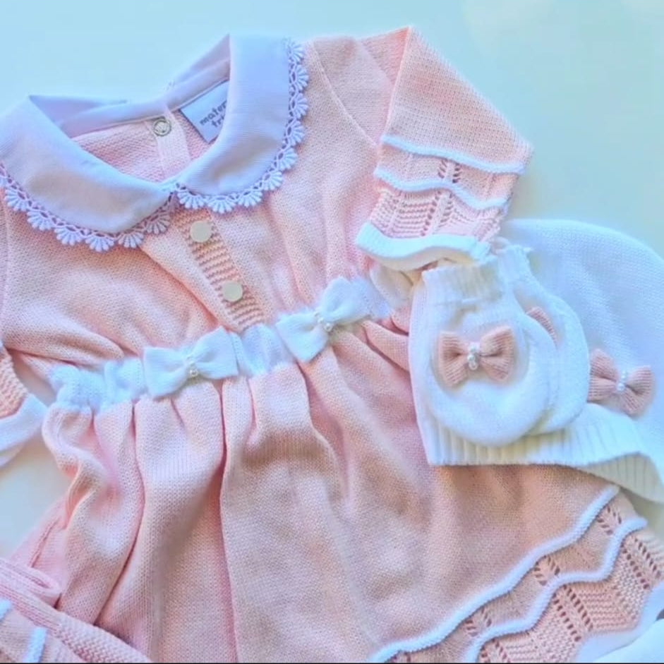 Pink baby outfit with white lace details on a light blue background