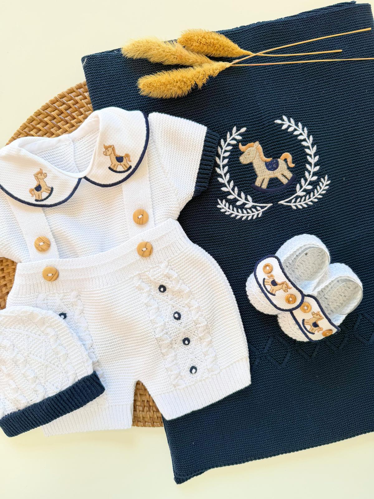 Children's outfit with white jacket, navy pants, and shoes on a textured surface.