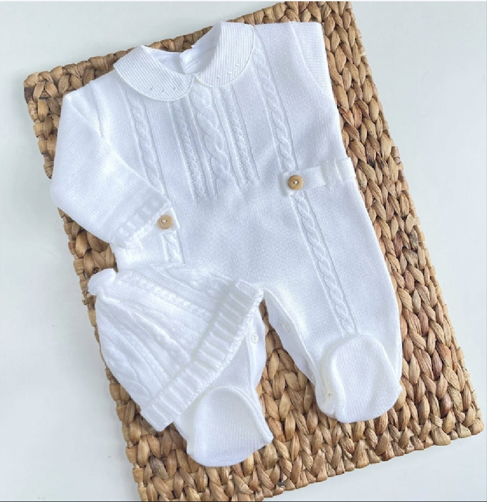 White baby outfit with brown buttons on a woven mat