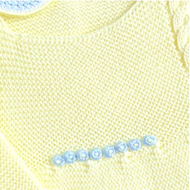 Close-up of a yellow knitted garment with blue floral embroidery. Yellow baby romper with blue trim knitted made with cotton,  newborn boy take me home outfit