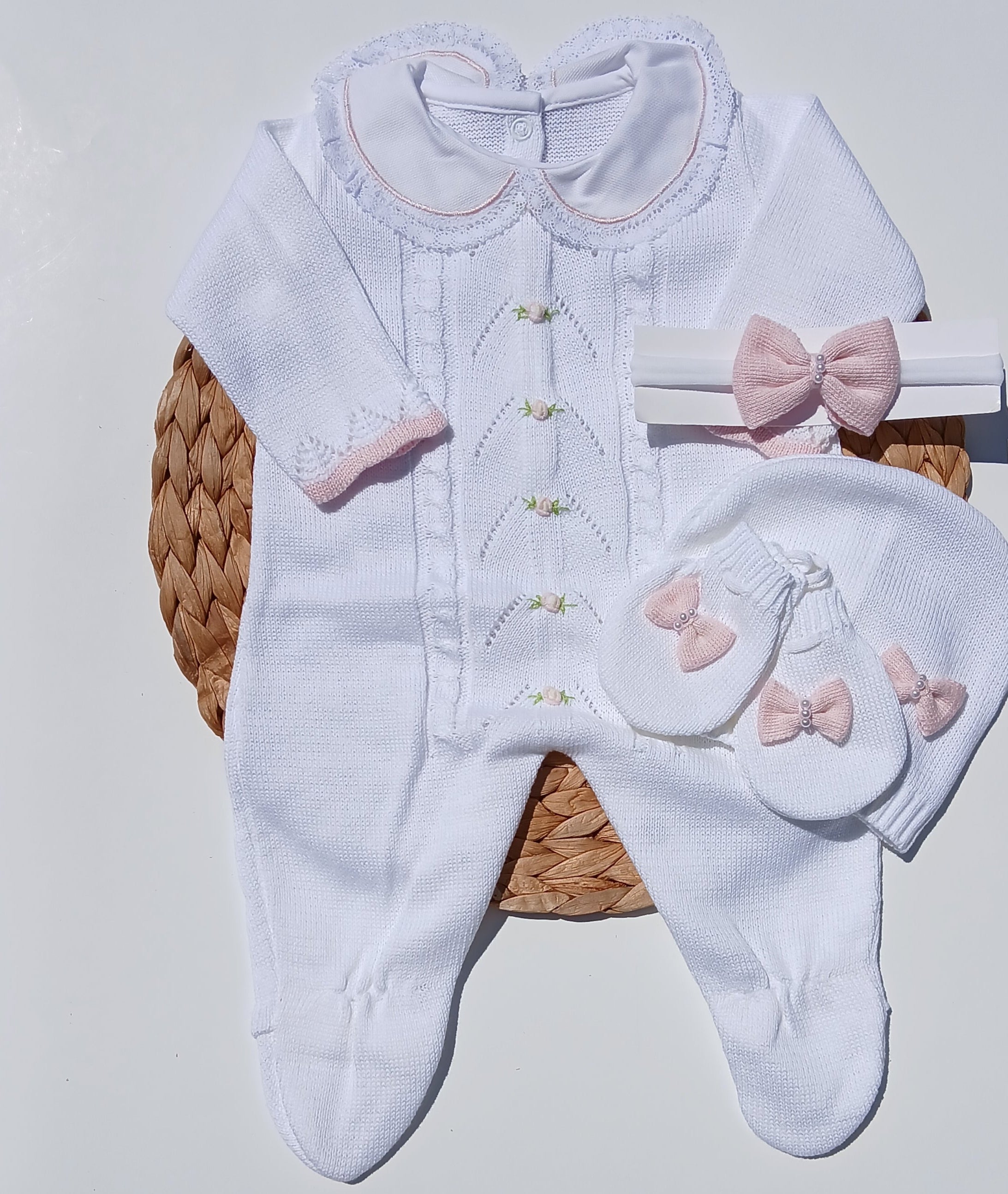 White baby outfit with pink bows on a white surface