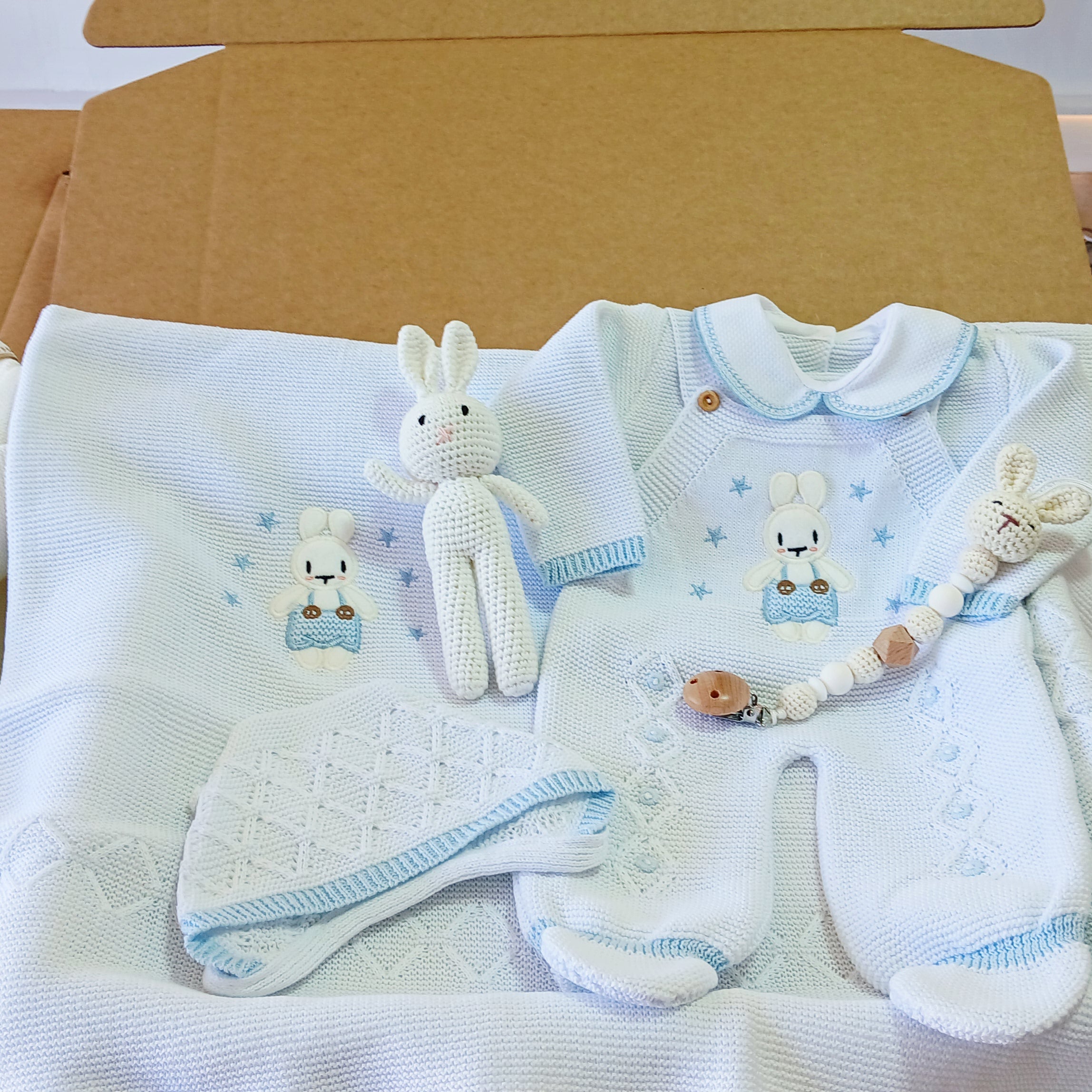 Baby clothing set with onesie, hat, and blanket on a table
