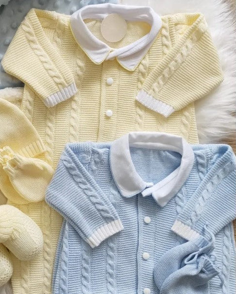 Set of baby knitted cardigans and accessories in yellow and blue on a textured surface.