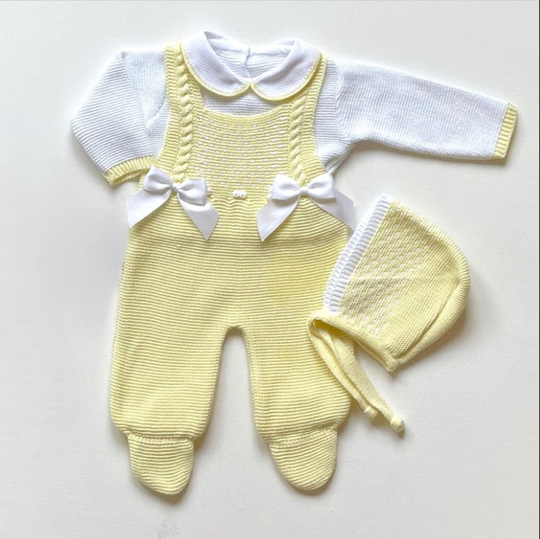 Yellow knitted baby outfit with white shirt and bonnet on a light background