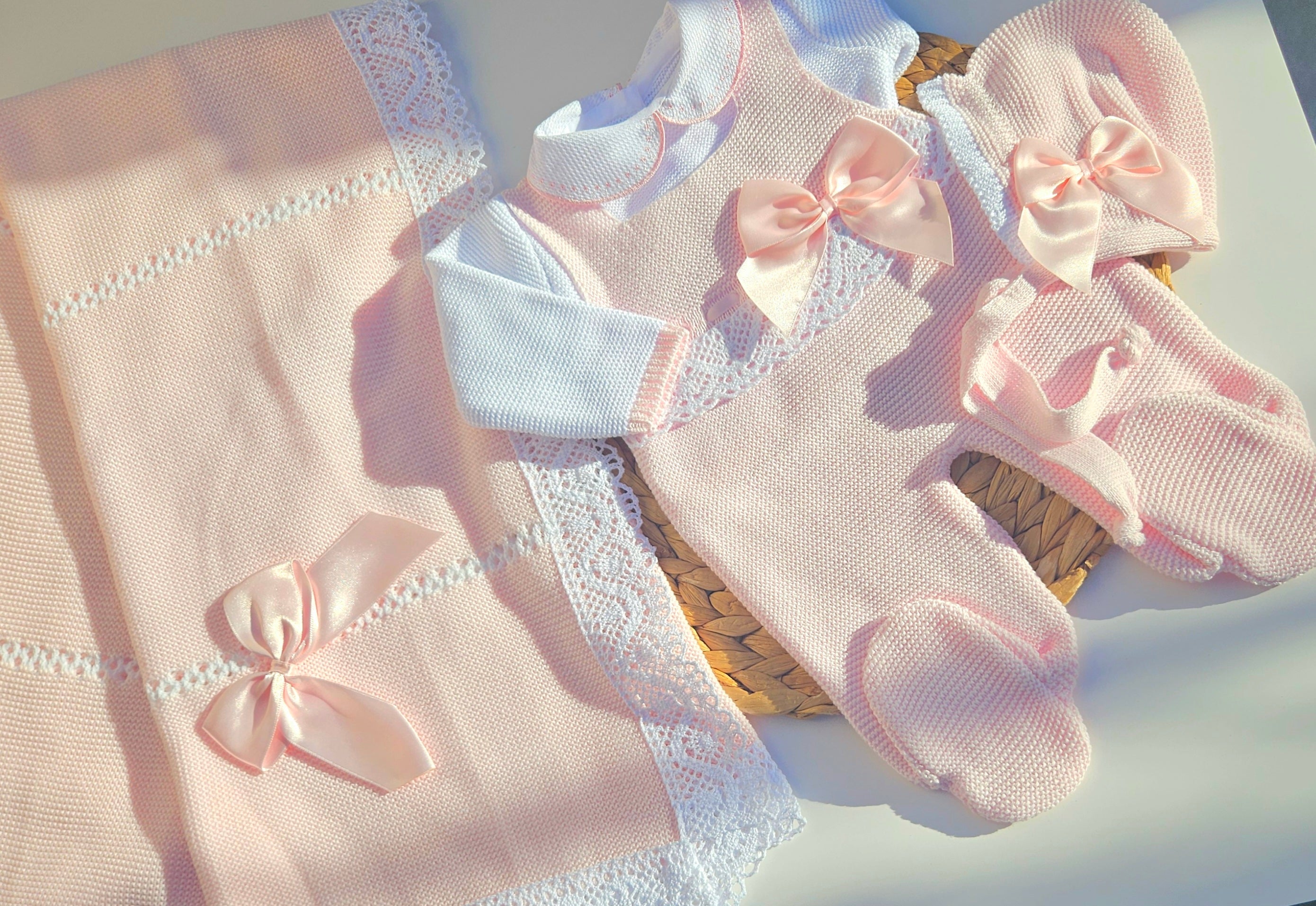 Pair of pink baby socks with bows on a white surface