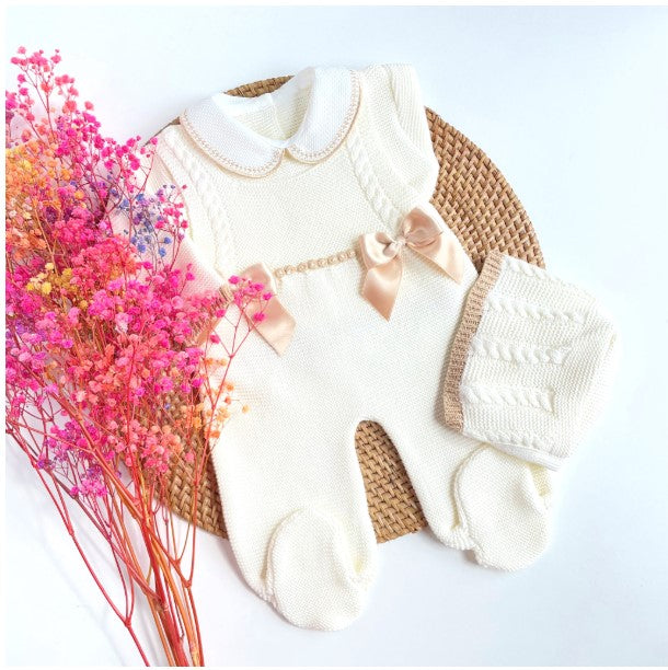 Baby outfit with Ivory romper, hat, and mittens on a light background with pink flowers. Camel bow, Newborn knit Coming home outfit