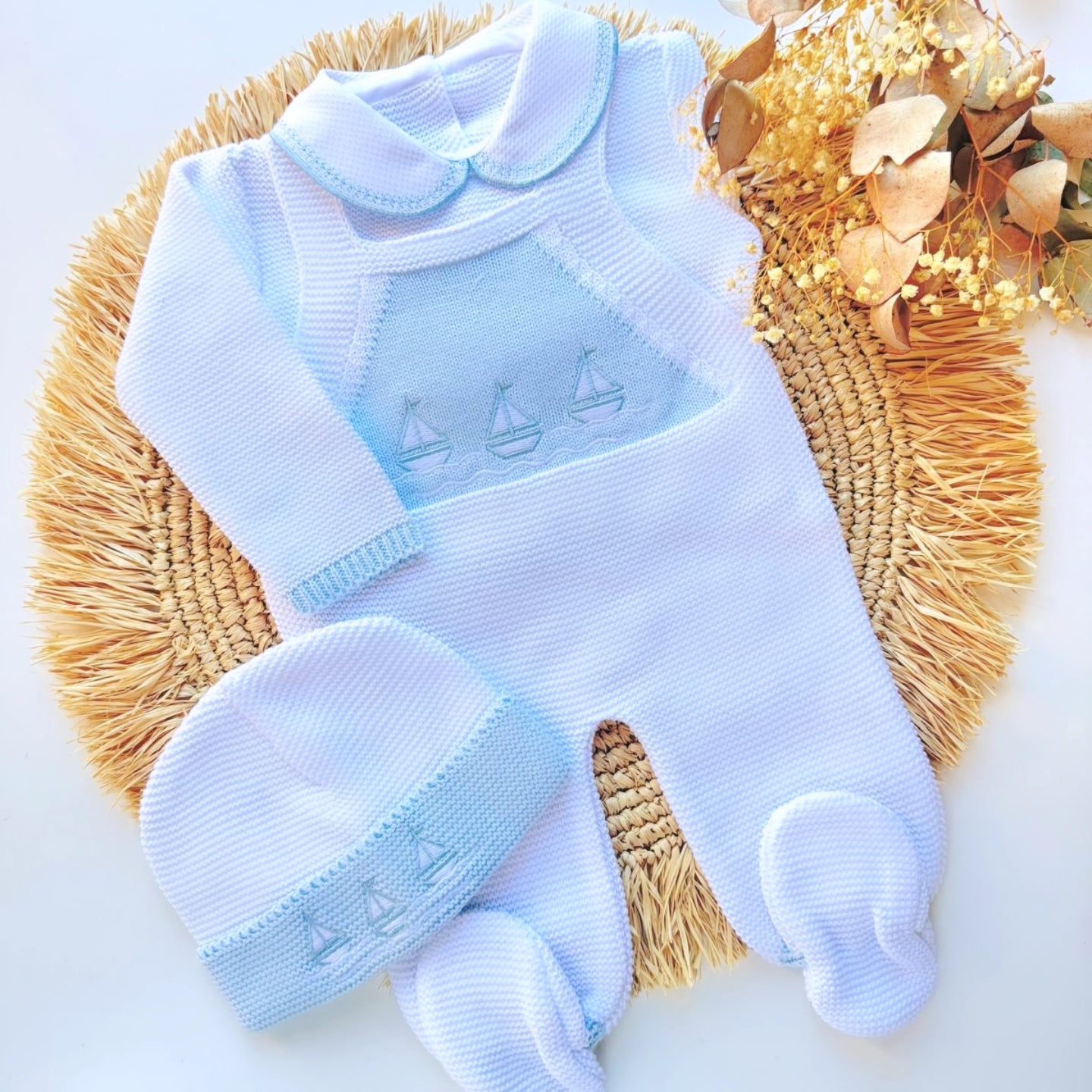 Blue baby outfit with matching hat on a woven mat. newborn sailor navy