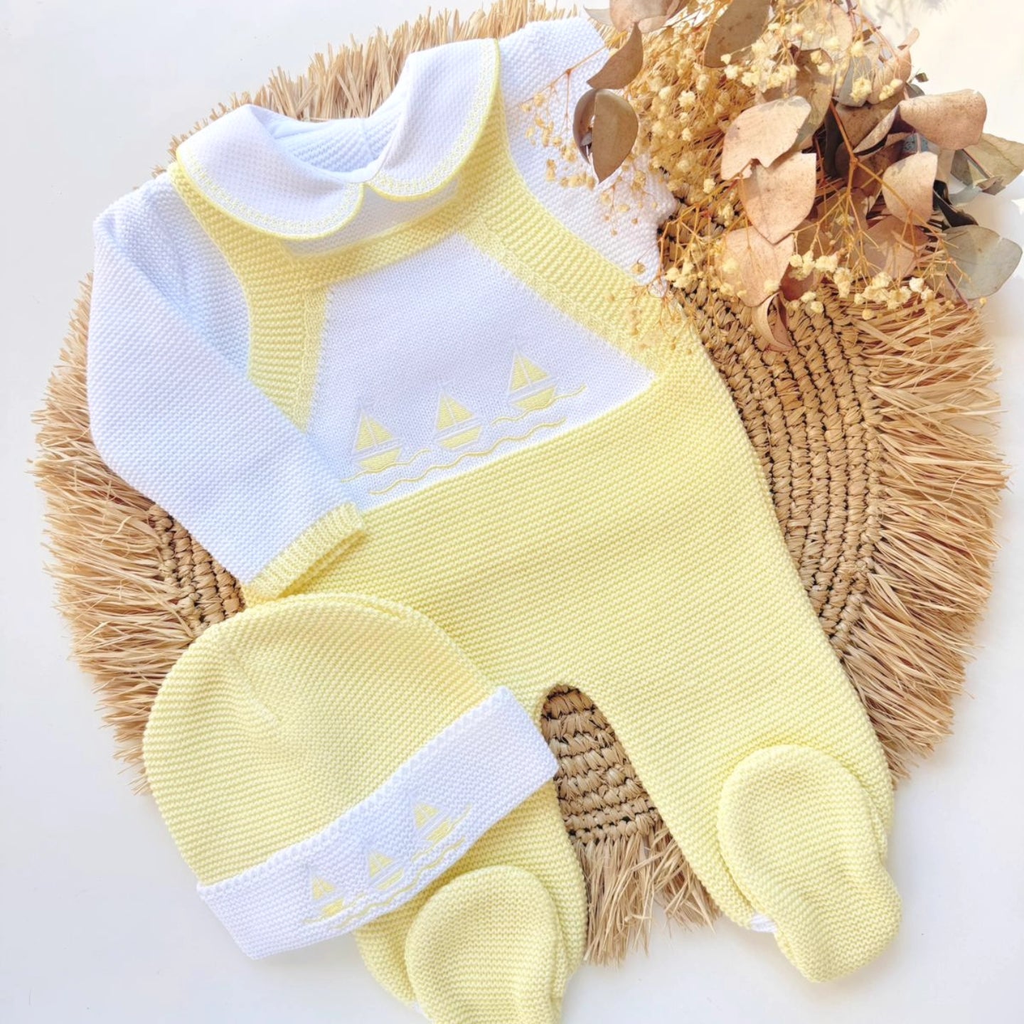 Yellow baby outfit with white trim on a woven mat sailor navy