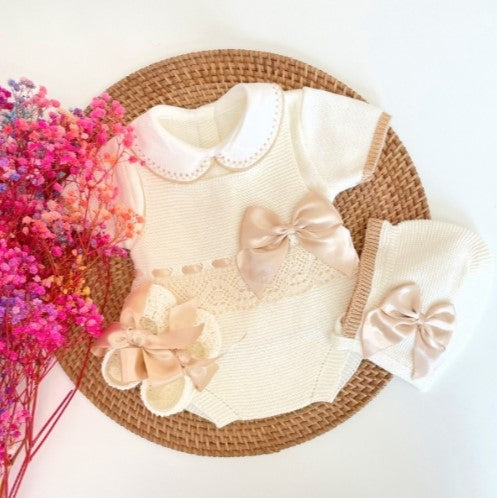 Baby outfit with floral details on a woven basket against a white background