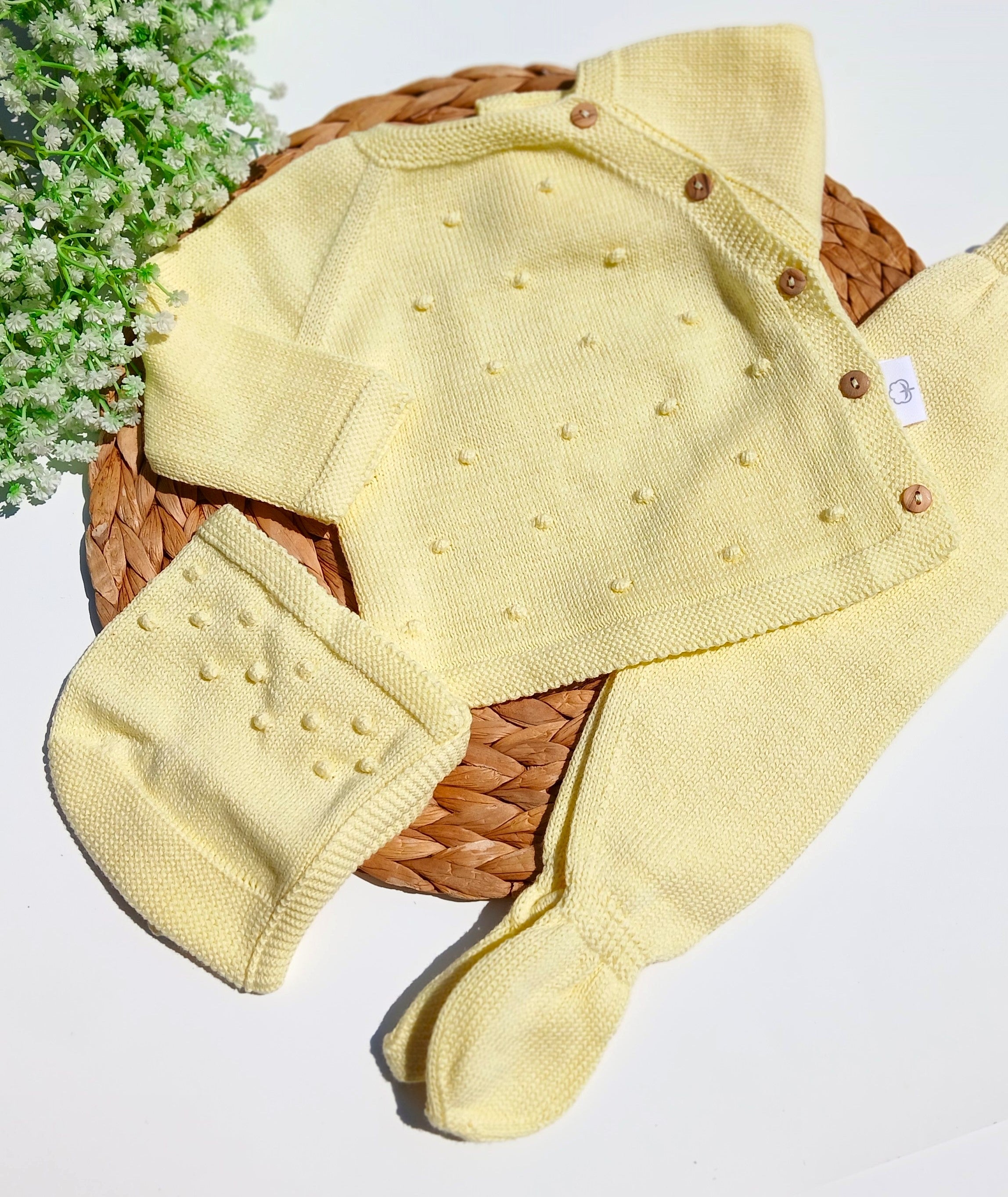 Yellow baby outfit with hat and booties on a white background