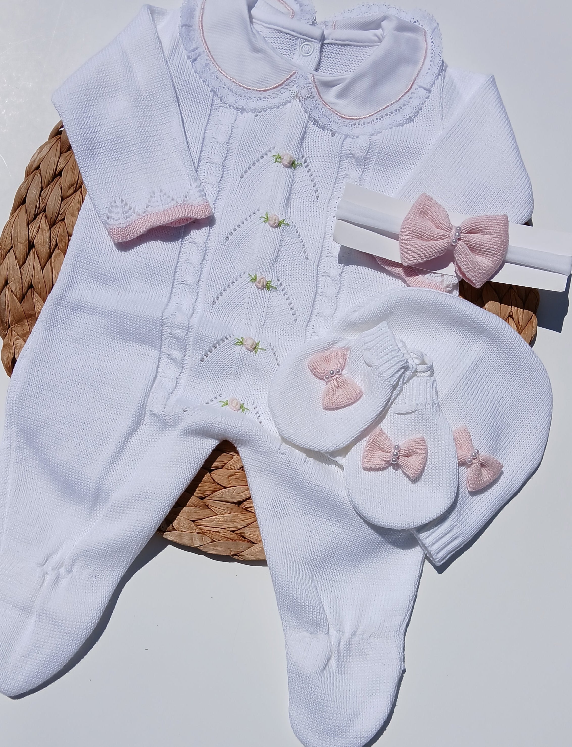 White baby outfit with pink bows on a white surface
